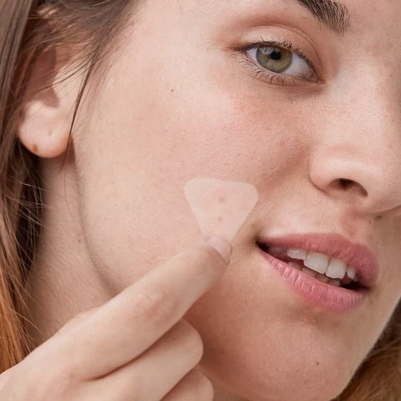 Female applying PanOxyl Blemish Aftercare Brightening Patch to her cheek to show size and clarity of patch.