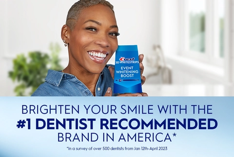 Woman smiling holding Crest 3DWhitestrips Event Whitening Boost pack. Brighten Your Smile with the #1 Dentist Recommended Brand in America.