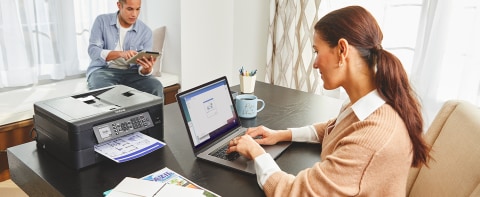 Woman in home office printing documents wirelessly from laptop computer