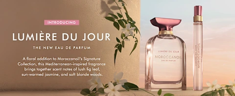 Moroccanoil Lumière du Jour Eau de Parfum bottle and travel spray with floral accents on warm sunset background
