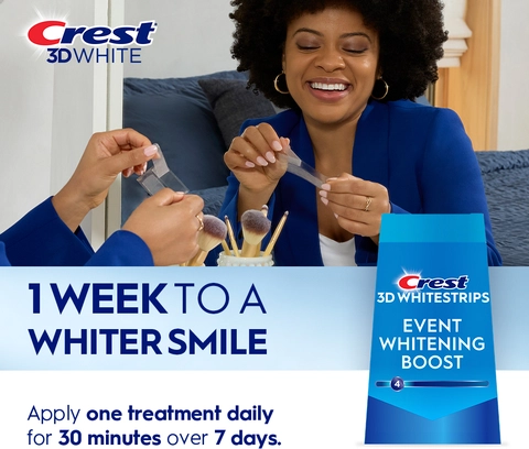 Reflection of woman in mirror smiling and peeling a Crest 3DWhitestrip. 1 Week to a Whiter Smile.