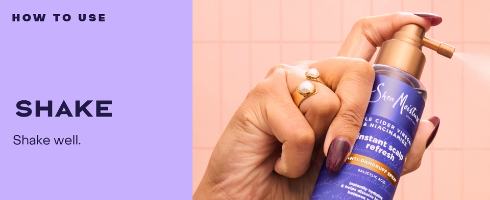 Text reads: "HOW TO USE: SHAKE. Shake well." A woman's hand holds SheaMoisture spray bottle with golden cap, set against a soft pink tiled background.