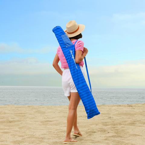 Woman carrying umbrella in storage bag on the beach.