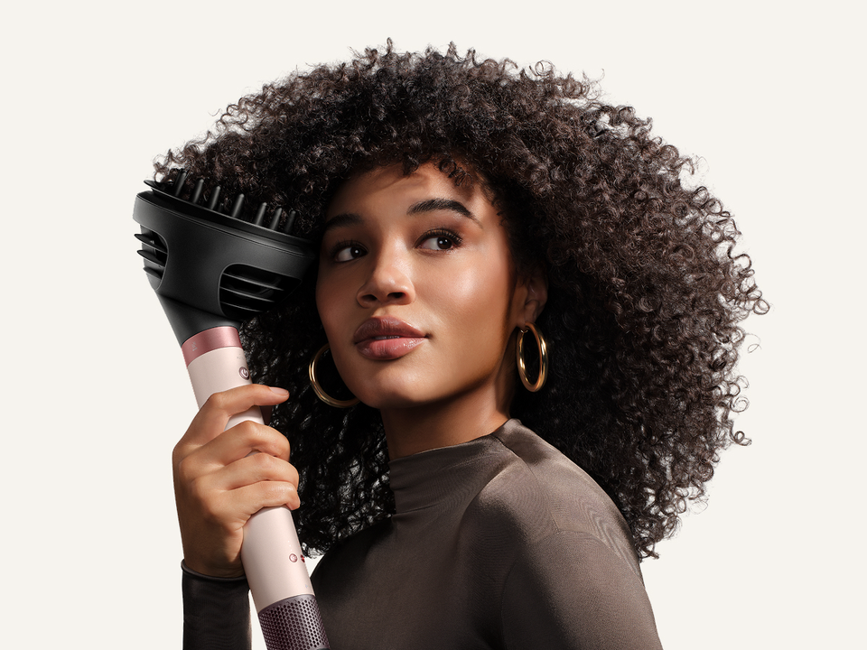 Model diffuses her hair with the Dyson Wave+Curl diffuser 2x.