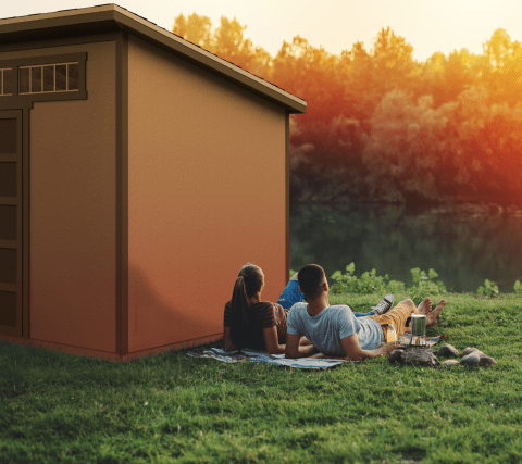 Couple laying next to montague shed in backyard watching sunset.