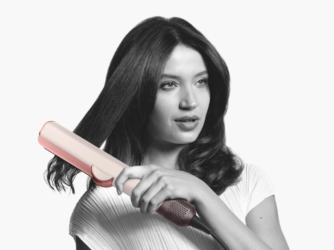 Model straightening hair with Dyson Airstrait hair straightener in ceramic pink and rose gold