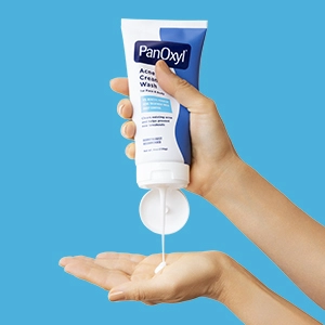 A hand squeezing PanOxyl Acne Creamy Wash into another open hand below.