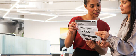 Two women in corporate office reviewing black and white business investment document printed with Brother Genuine toner