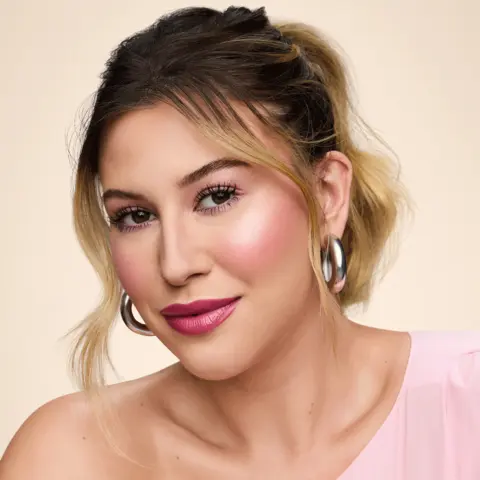 Gif em que temos a Niina, uma mulher branca de cabelo castanho preso, com a aplicação do produto Blush Daily Stick no rosto em duas poses diferentes.