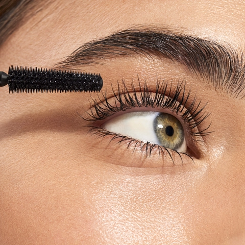 Model holding Lash Xtndr Mascara in hand with a close shot of lashes after using the mascara