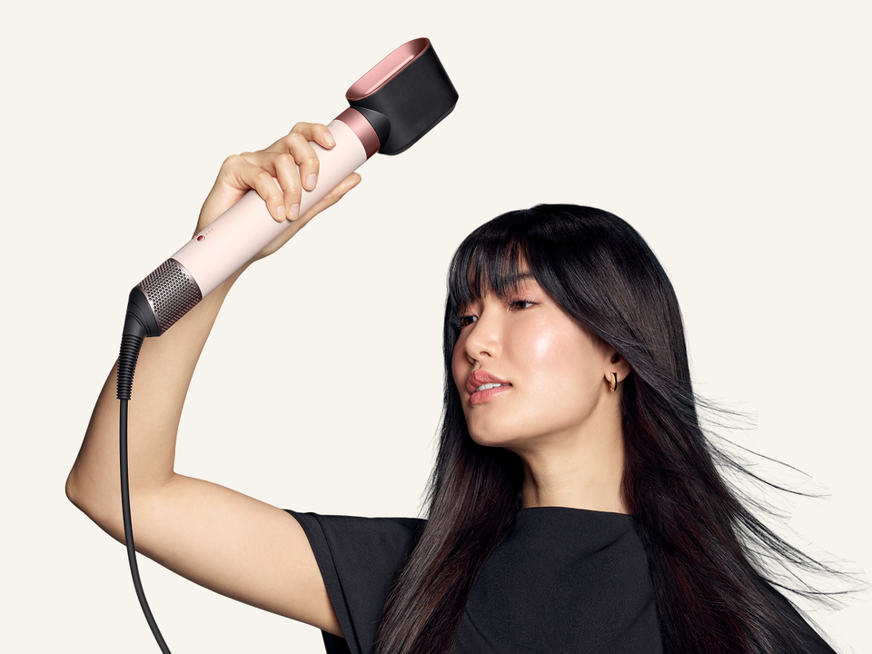 Model dries her hair with the Dyson Fast dryer 2x attachment.