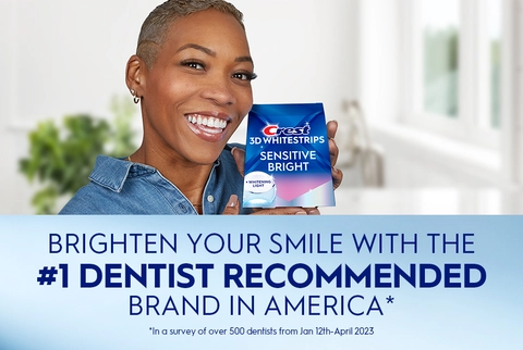 Woman smiling holding Crest 3DWhitestrips Sensitive Bright + Light pack. Brighten Your Smile with the #1 Dentist Recommended Brand in America.