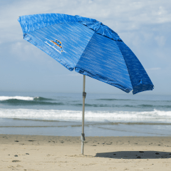 Open, tilted beach umbrella on the beach with ocean in the background. 