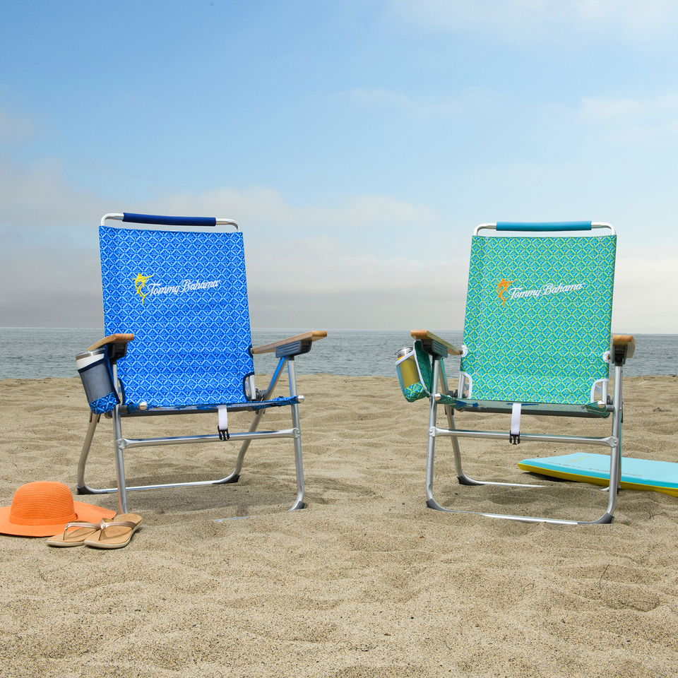 Two chairs on the beach by the water.