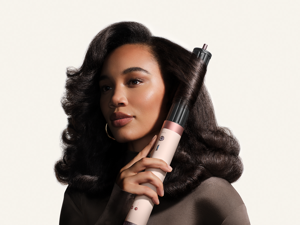 Model curls her hair with the Dyson 1.6in Co-anda2x curling barrel.