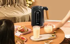 Two people enjoying beverage on a table with the nut milk maker.