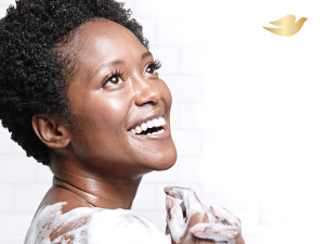 A smiling woman with short hair lathering with Dove body wash, set against a soft white background.
