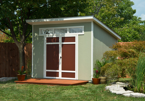 Shed in backyard under a tree with a deck attached to it