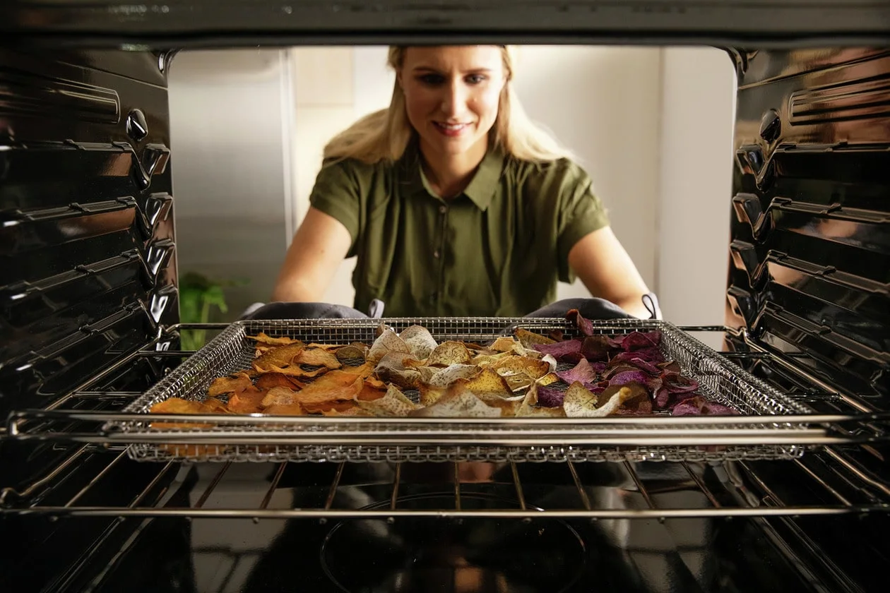 A woman places a tray of food in an Electrolux air fryer range