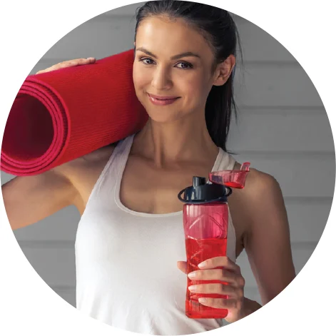 Healthy woman holds Juce Garden Berry in her water bottle and holds yoga mat