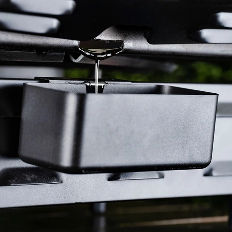 A rear grease cup on the back of the griddle catching grease draining off the griddle plate.