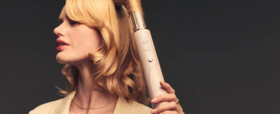 Blonde woman holding T3 Aire360 in her hair with curling attachment