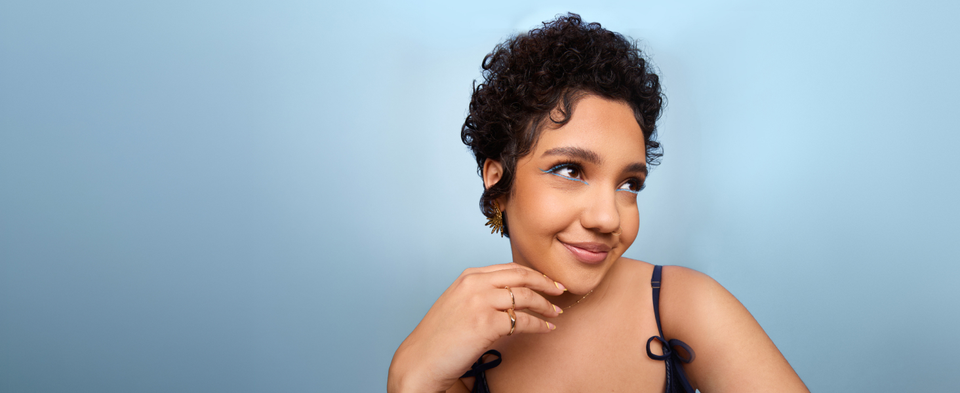 Smiling woman with a short curly style on a light blue background.