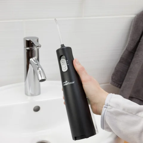 Hand Holding Black Cordless Express Water Flosser WF-02  in Bathroom