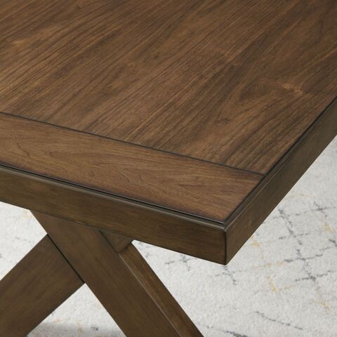 Close-up image of the end of the table, showing the rich textures and brown color of the finish, with a view of  the X-shaped base