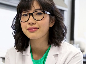 Woman wearing glasses & a white lab coat reminding you to establish a healthy oral care routine