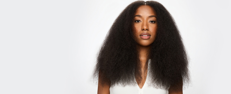 Woman with voluminous blown-out natural hair on a green background.