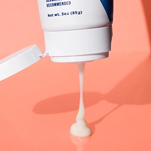 An open tube of Balancing Repair Moisturizer squeezing out a small dollop of white creamy product