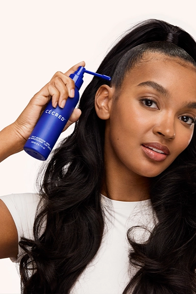 Woman applying Scalp Refreshing Spray to her scalp while in a protective style.