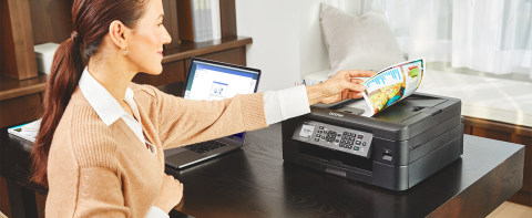 Woman placing double-sided color document into printer's automatic document feed for scanning