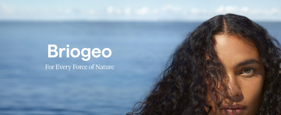 Person with curly hair by the ocean, with text 'Briogeo For Every Force of Nature'.