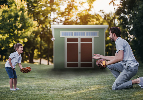 Dad playing catch with his son in the backyard in front of the Aston shed.