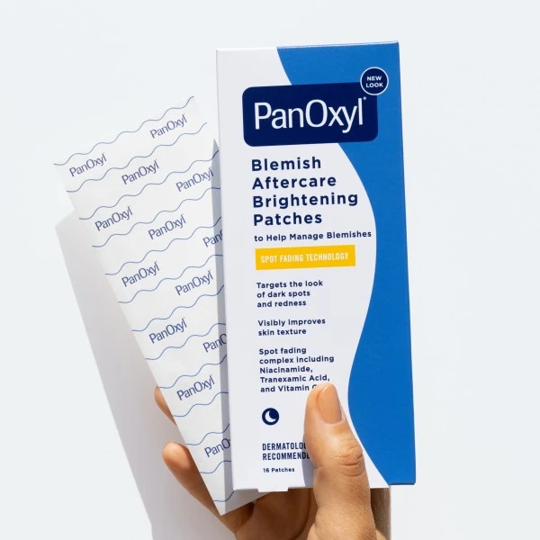 Hand holding PanOxyl Blemish Aftercare Brightening Patches showing the inner sheet of patches with the PanOxyl logo.