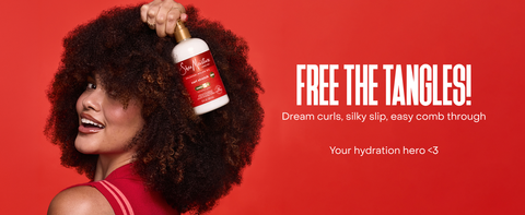 A woman with voluminous curls holds a SheaMoisture bottle against a bold red backdrop.