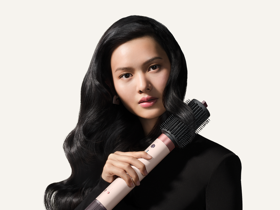Model styles her hair with the Dyson Large round volumizing brush 2x.