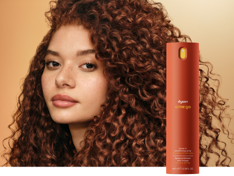A curly haired model shows off her nourished hair after using Dyson Omega products.