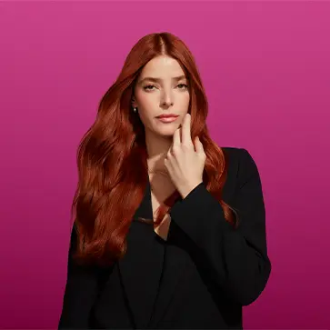 Image of same woman with auburn hair dressed in black and raising her left hand to touch her healthy, vibrant hair.