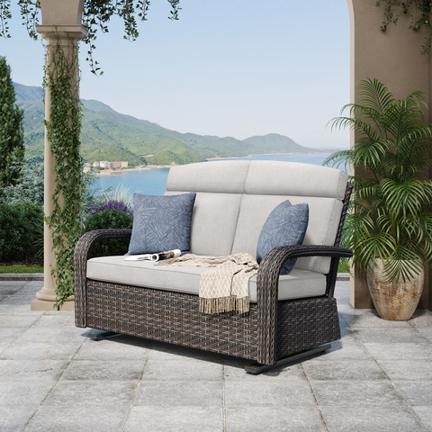 wicker glider loveseat with cushions and pillows on a patio