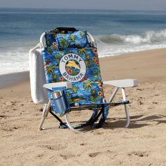 Tropical patterned Tommy Bahama branded beach chair on the beach with towel hanging on the back of the chair. 