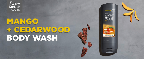 Bottle of Dove Men+Care Body Wash on gray stone with cedarwood pieces and mango slices.