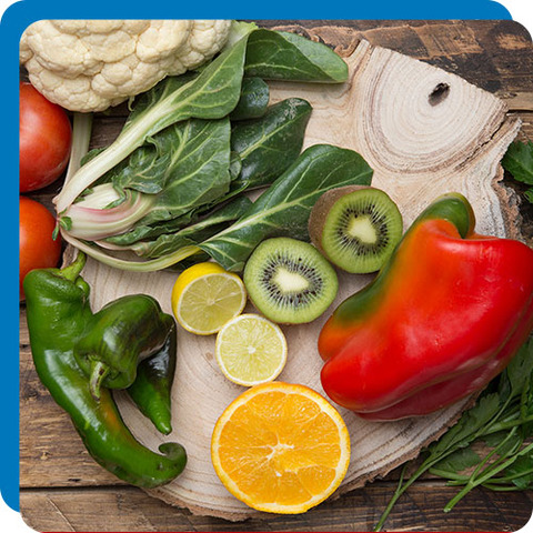 Kiwi, Collard Greens, Chili, Bell Pepper, Cauliflower, Tomato, Lemon in a chopping board