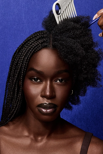Woman get her hair taken down from braids with large comb