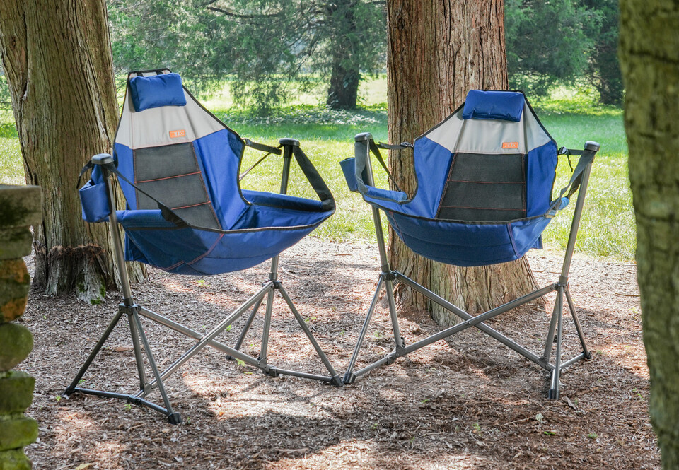 Two swinging hammock chairs in lightly wooded area.