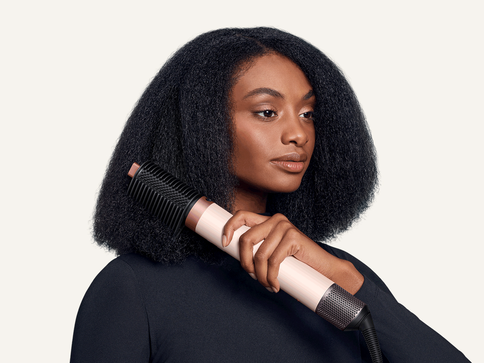 Model smooths her hair with the Tension comb 2x attachment.