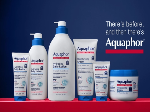 Aquaphor Healing Dry Skin product line displayed on red and blue background: Hydrating Daily Lotion and Moisturizing Cream in multiple sizes with text "There's before, and then there's Aquaphor