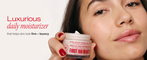 Woman holding firming day cream near her cheek
